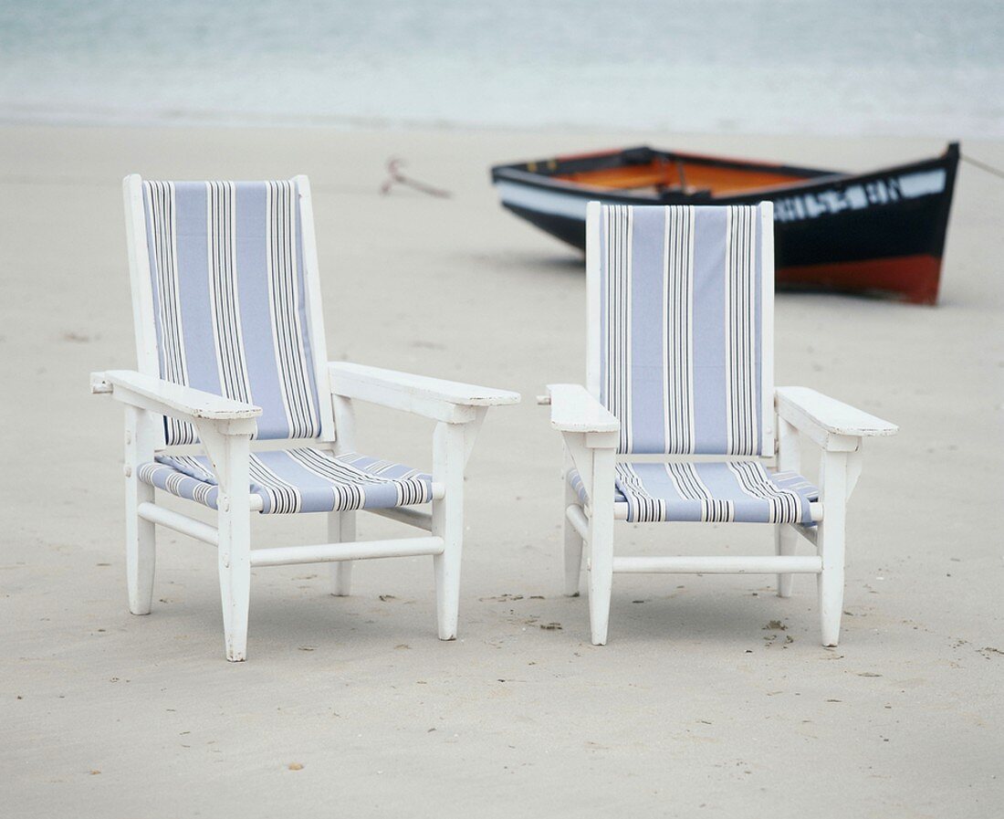 Zwei Stühle und ein Boot am Strand