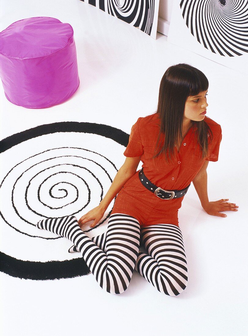 Young woman wearing striped tights sitting on rug