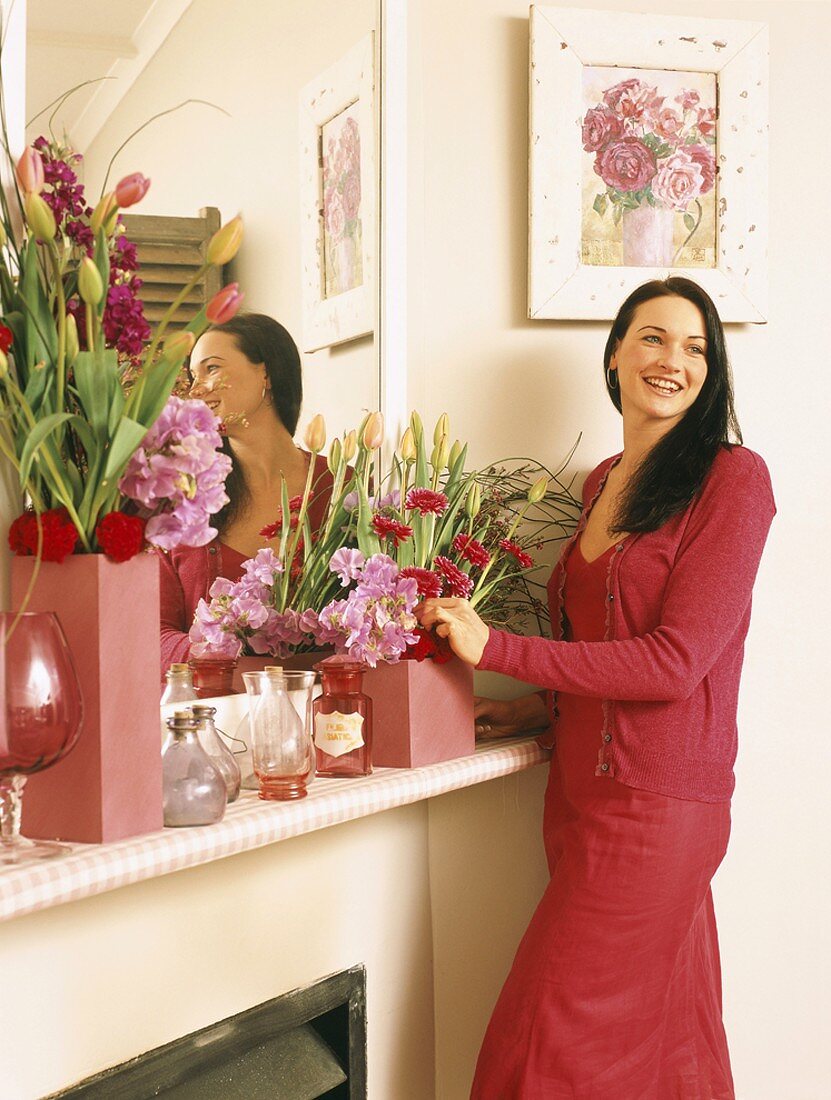 Woman arranging flowers on mantelpiece