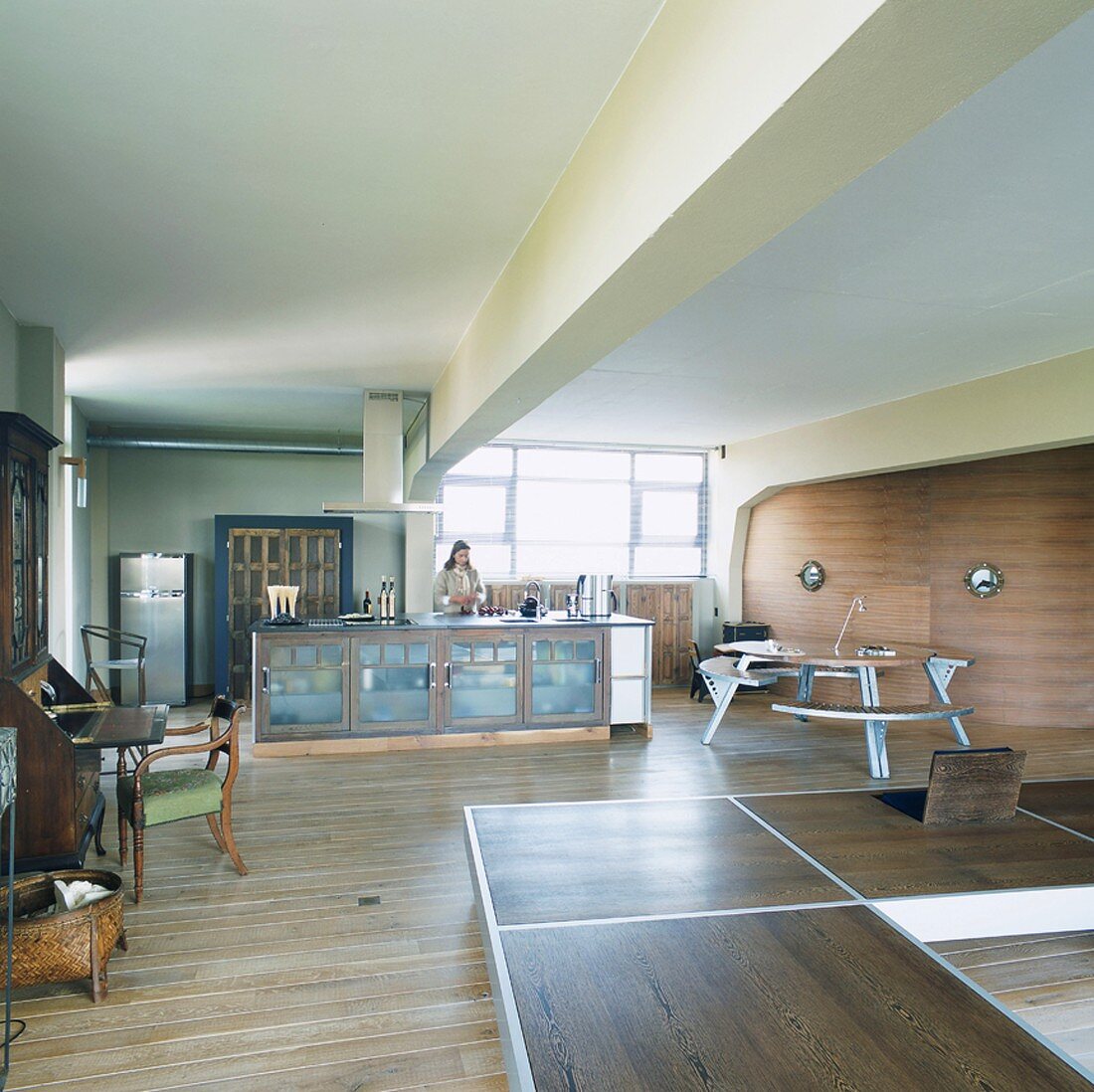 Woman in loft apartment kitchen-dining room with modern & antique furniture