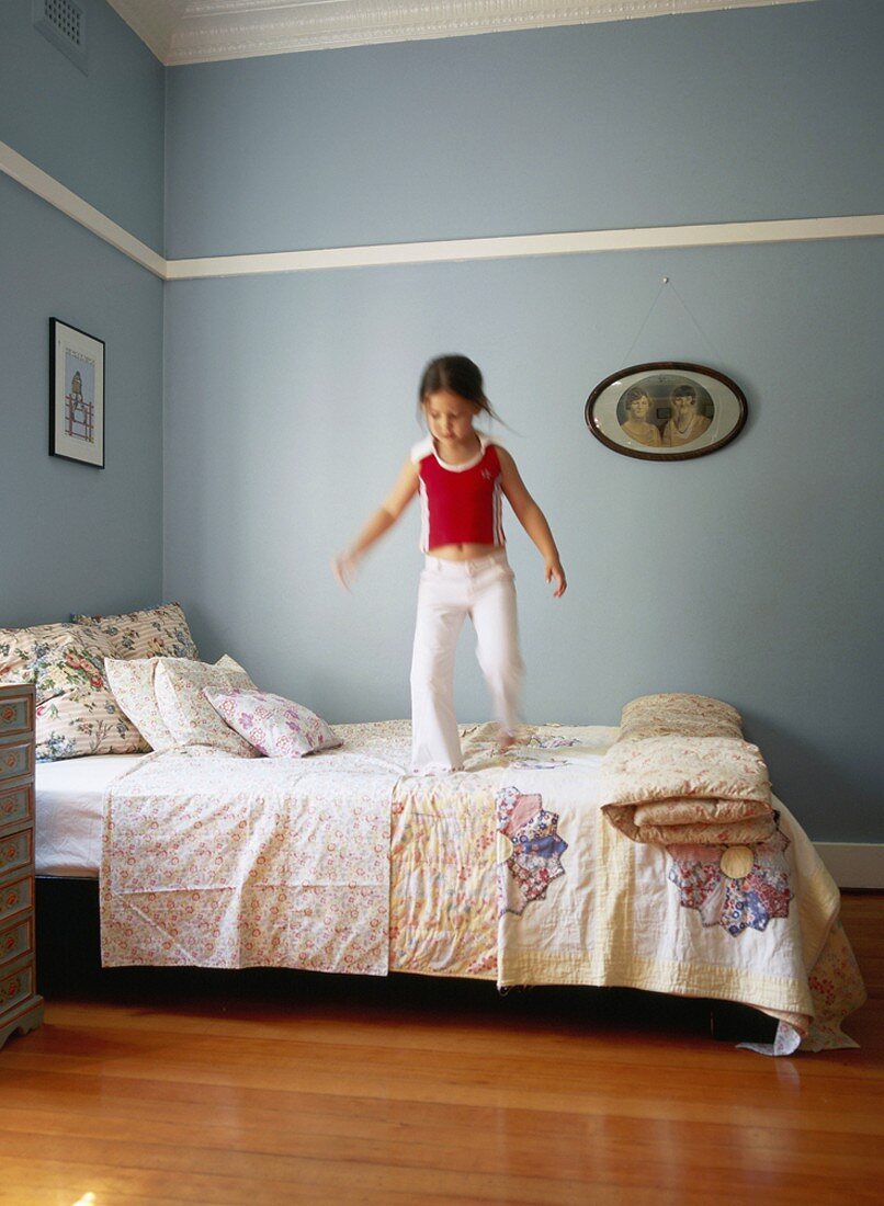 Little girl bouncing on bed
