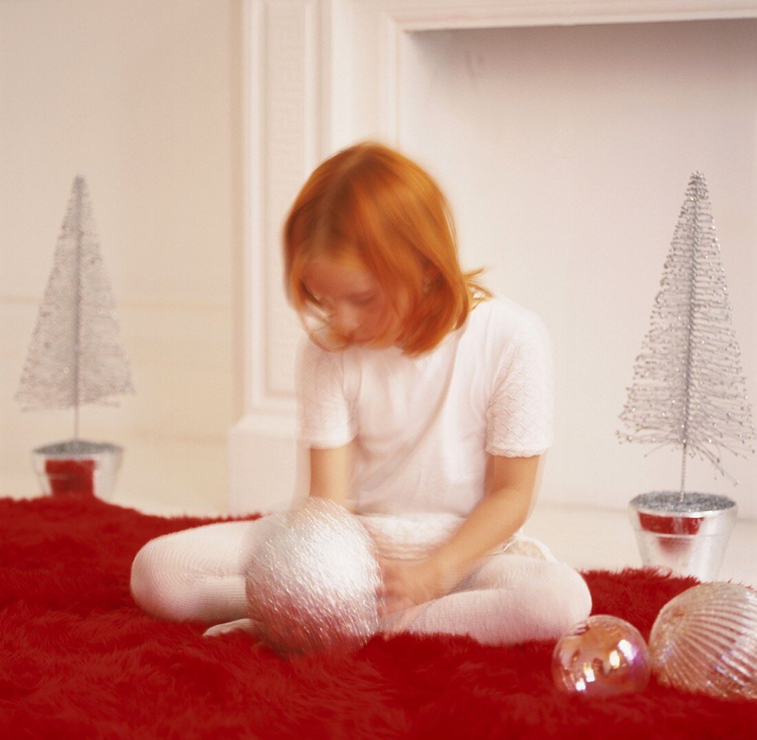Mädchen spielt mit Weihnachtsdekoration