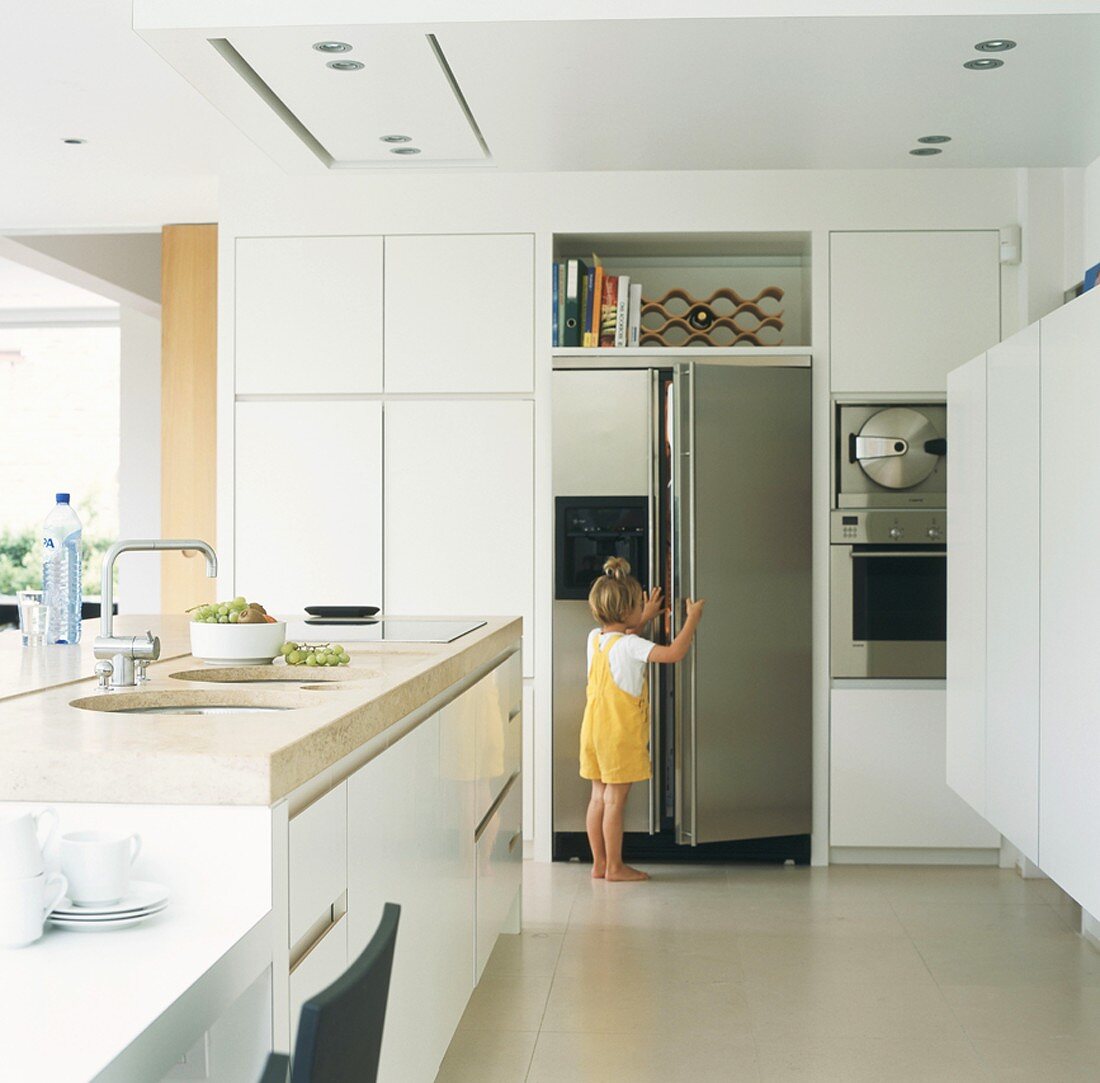 Kleines Mädchen öffnet den Kühlschrank in der Küche