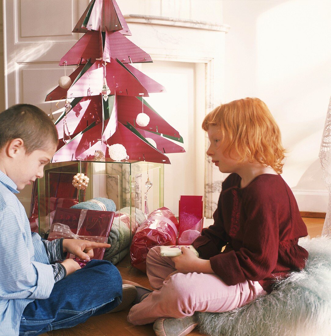 Zwei Kinder packen Weihnachtsgeschenke aus