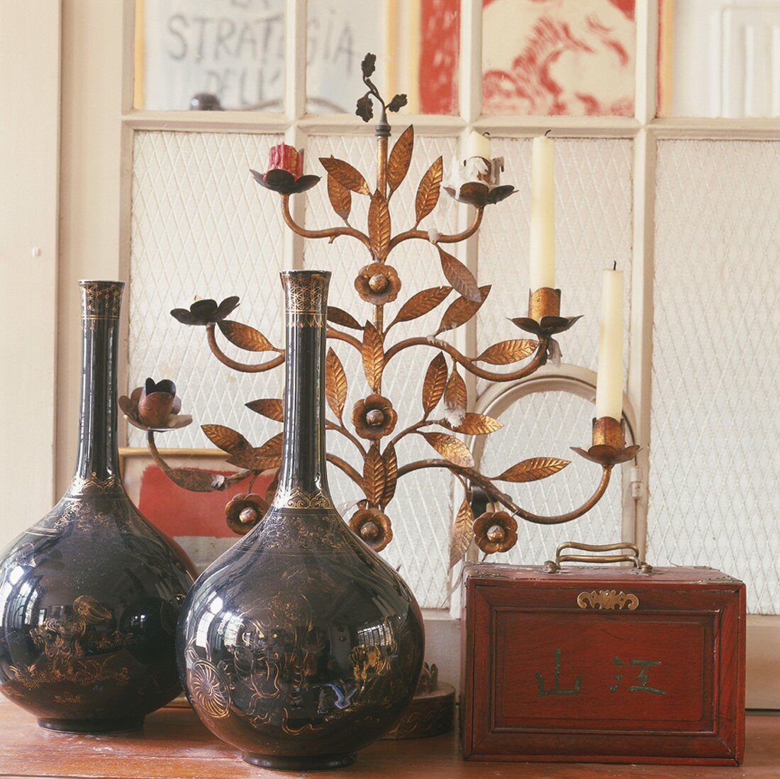 Porzellanvasen, Holzkästchen und floraler Kerzenständer aus Bronze vor einem Sprossenfenster