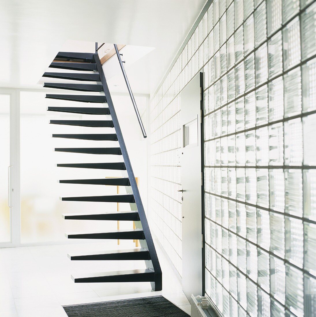 Asymmetrische Treppe in einem weissen Raum mit Glasbausteinwand