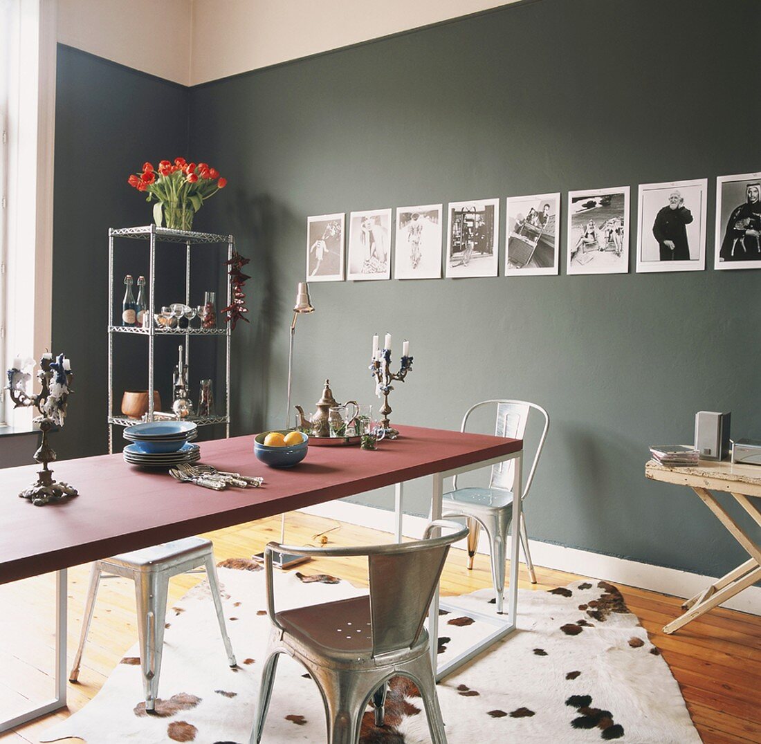 Designeresstisch mit Tolix Stühlen vor einer grünen Wand mit Fotoserie
