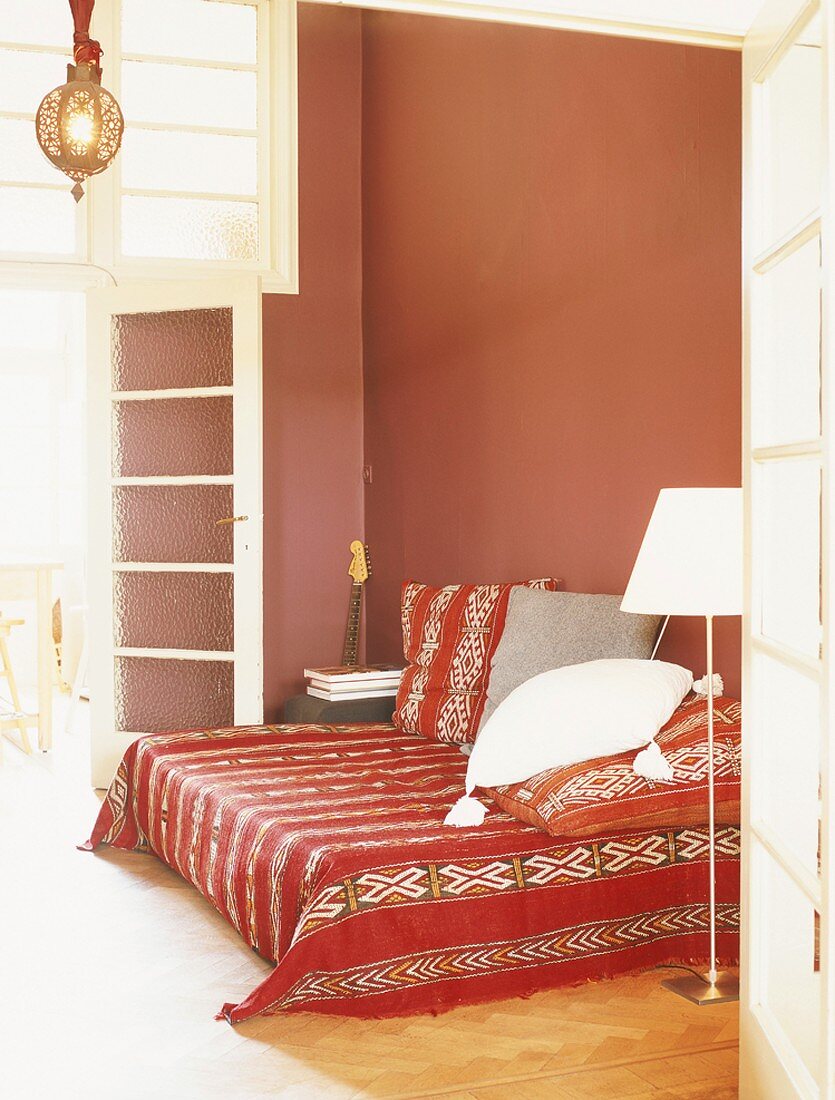 Rotes Schlafzimmer mit hoher Sprossenverglasung und Tagesbett im mexikanischen Stil