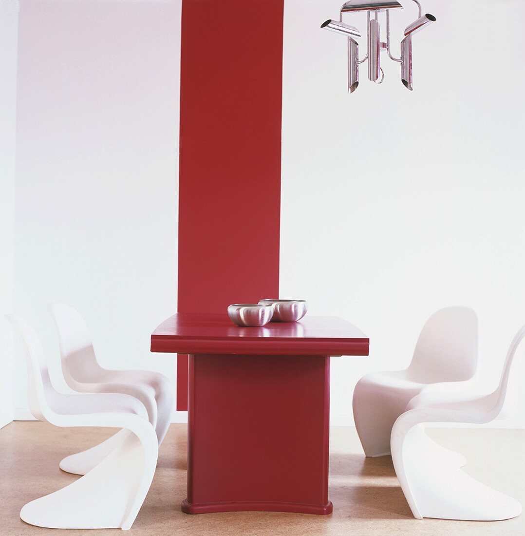 Ein roter Esstisch mit weissen Panton Stühlen