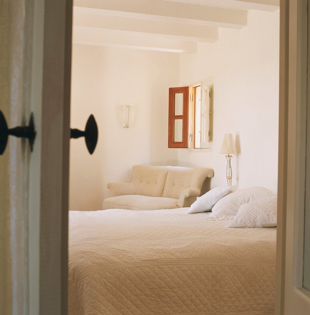 Blick in ein Schlafraum mit kleinem Fenster und sichtbaren Deckenbalken