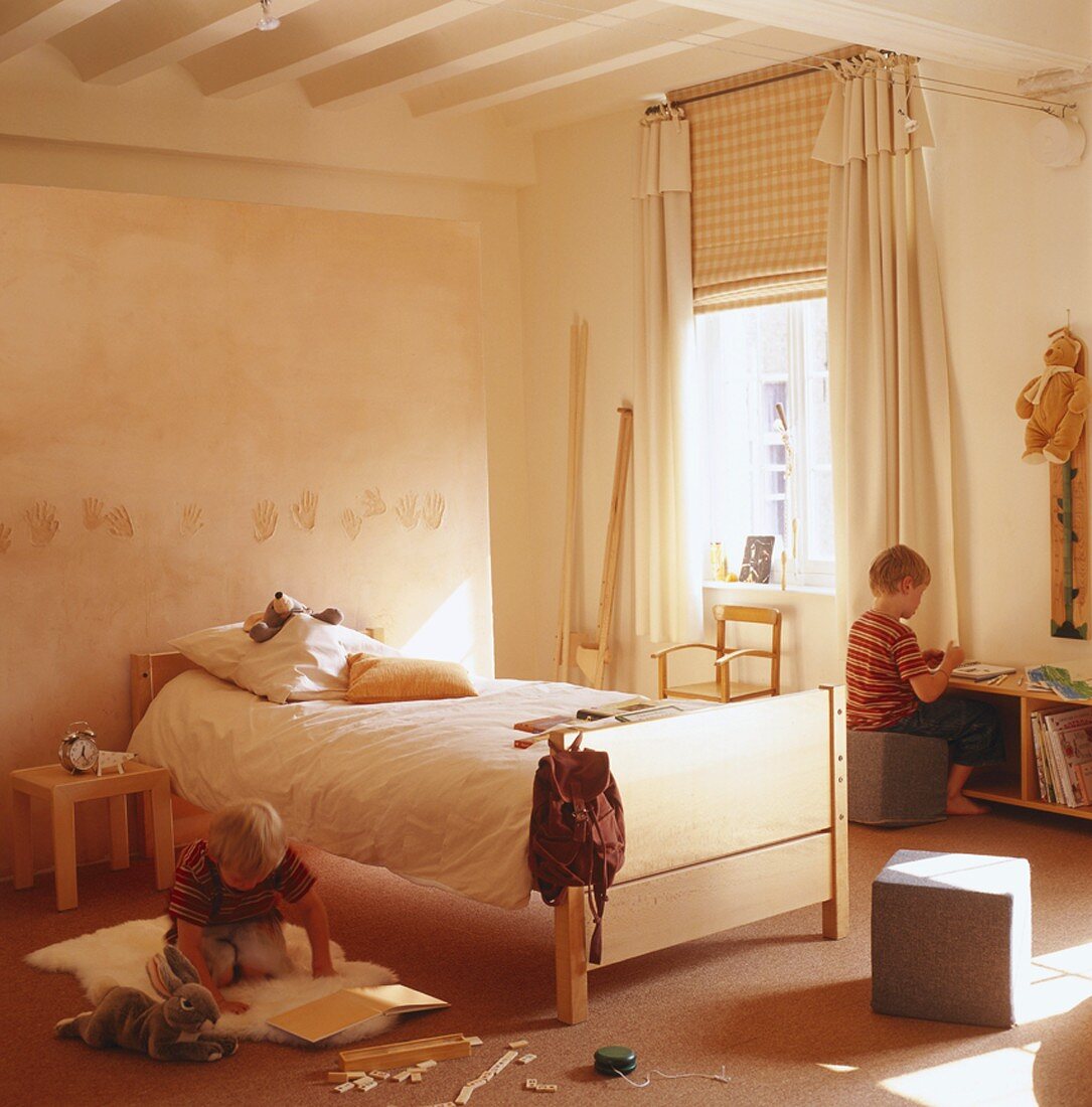 Ein Kinderzimmer mit Holzmöbeln in einem Raum mit sichtbaren Deckenbalken und einem hohen Fenster