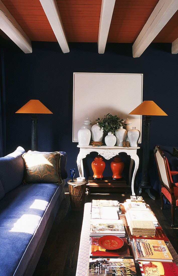 Farbkontraste in Rot- und Blautönen erzeugen Spannung in dem antik eingerichteten Wohnzimmer mit Holzbalkendecke