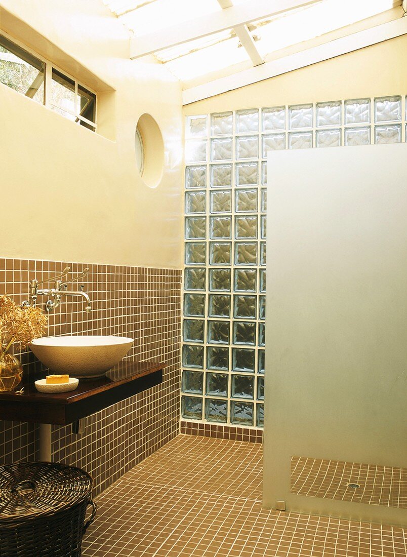Glasdach, Oberlichter und eine Wand aus Glasbausteinen schaffen Licht in dem gefliesten Bad mit offener Dusche