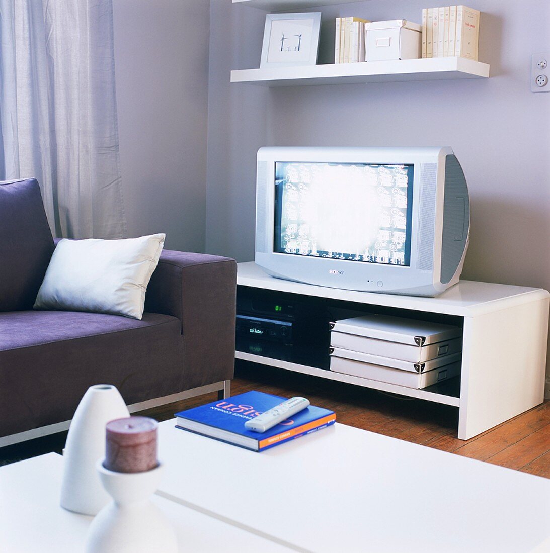 Schlichte TV Bank und ein Wandboard in Weiß in einem Wohnzimmer mit Dielenboden