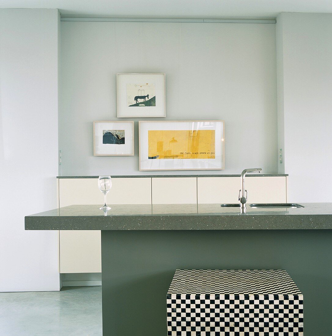 Eine schlichte Küchentheke mit Granitplatte vor eine Schranknische mit Bilderrahmen