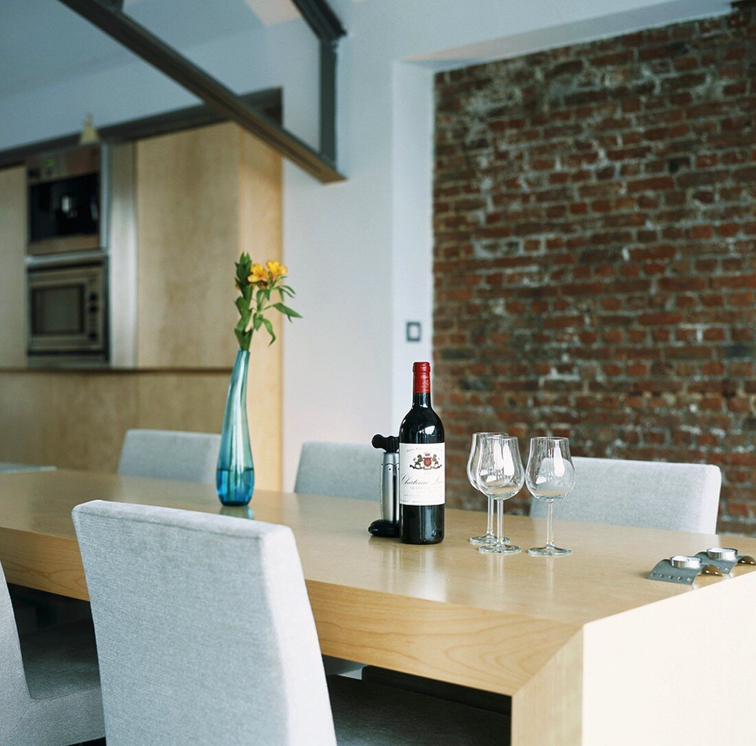 Rotweinflasche und Weingläser auf einem minimalistischen Holztisch