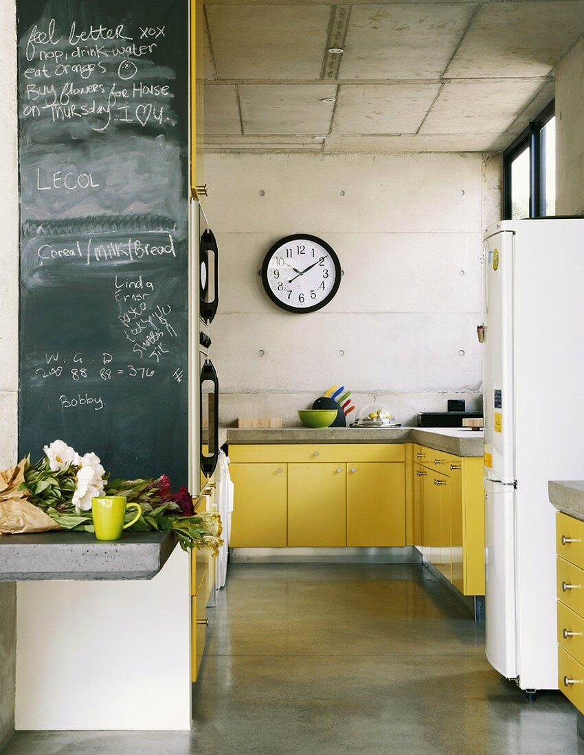 Leuchtend gelbe Küchentheken werten die rohen Betonwände der Küche auf