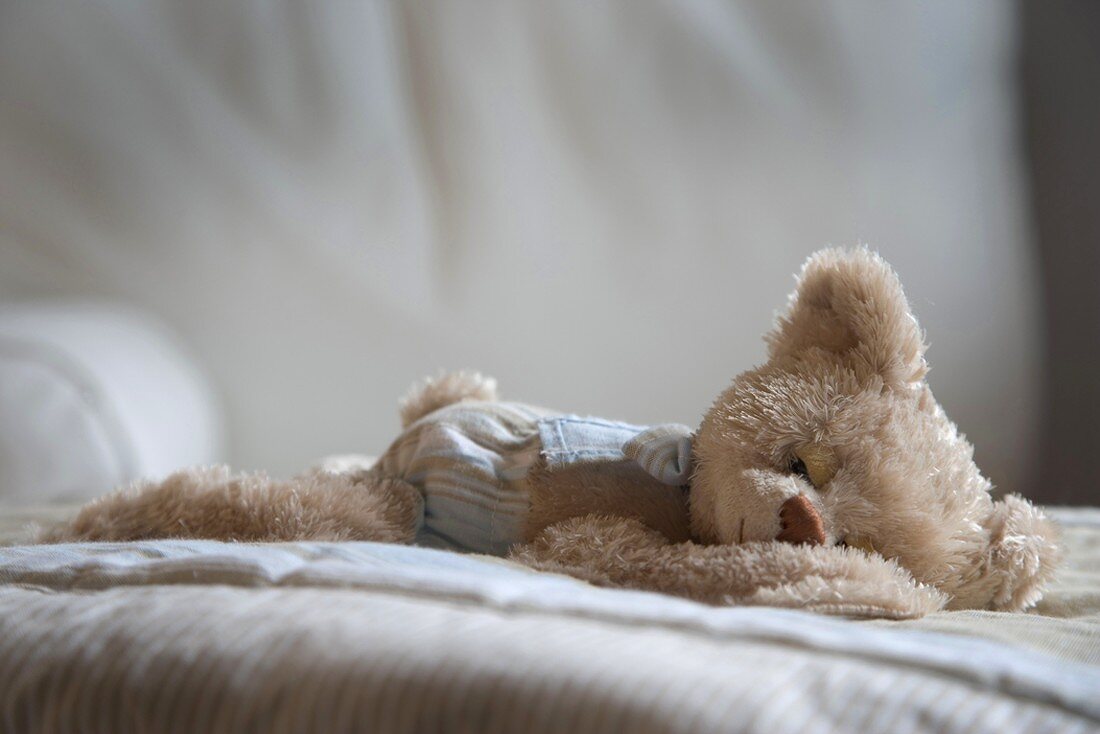 Ein Teddybär auf dem Bett liegend