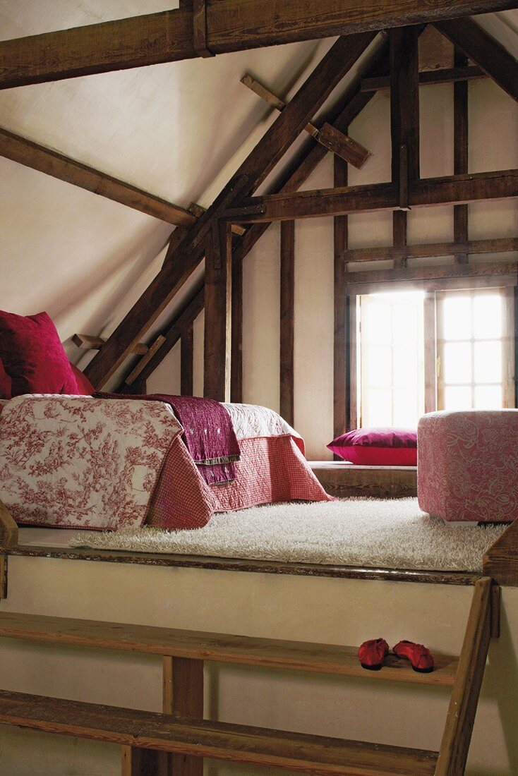 Gemütlicher Schlafbereich mit Hochflorteppich und rosa Stoffen auf einer Empore im offenen Dachraum