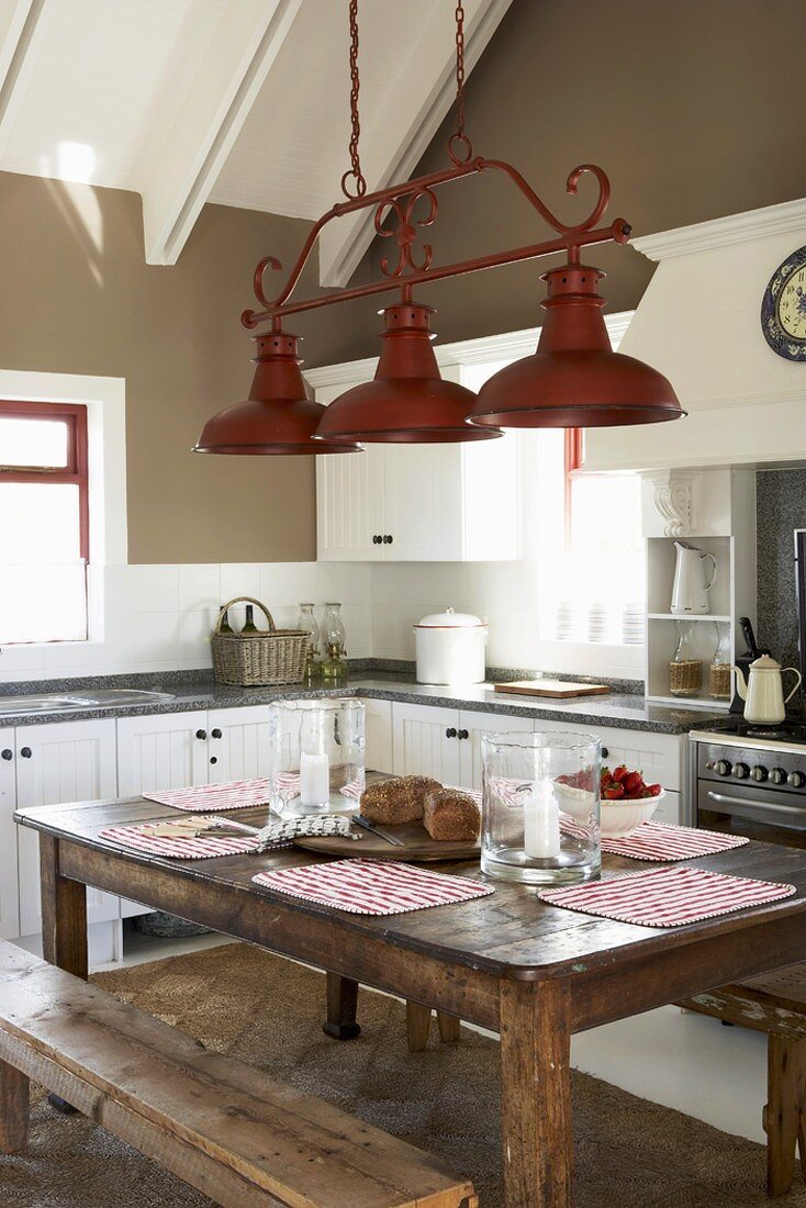 Ein rustikaler Holztisch mit Sitzbänken in einer klassischen Landhausküche mit Dachschräge