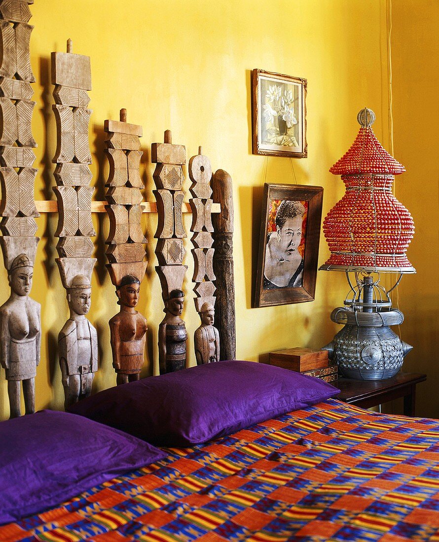 Originelles Kopfteil aus Holzskulpturen im bunten Schlafzimmer im afrikanischen Stil