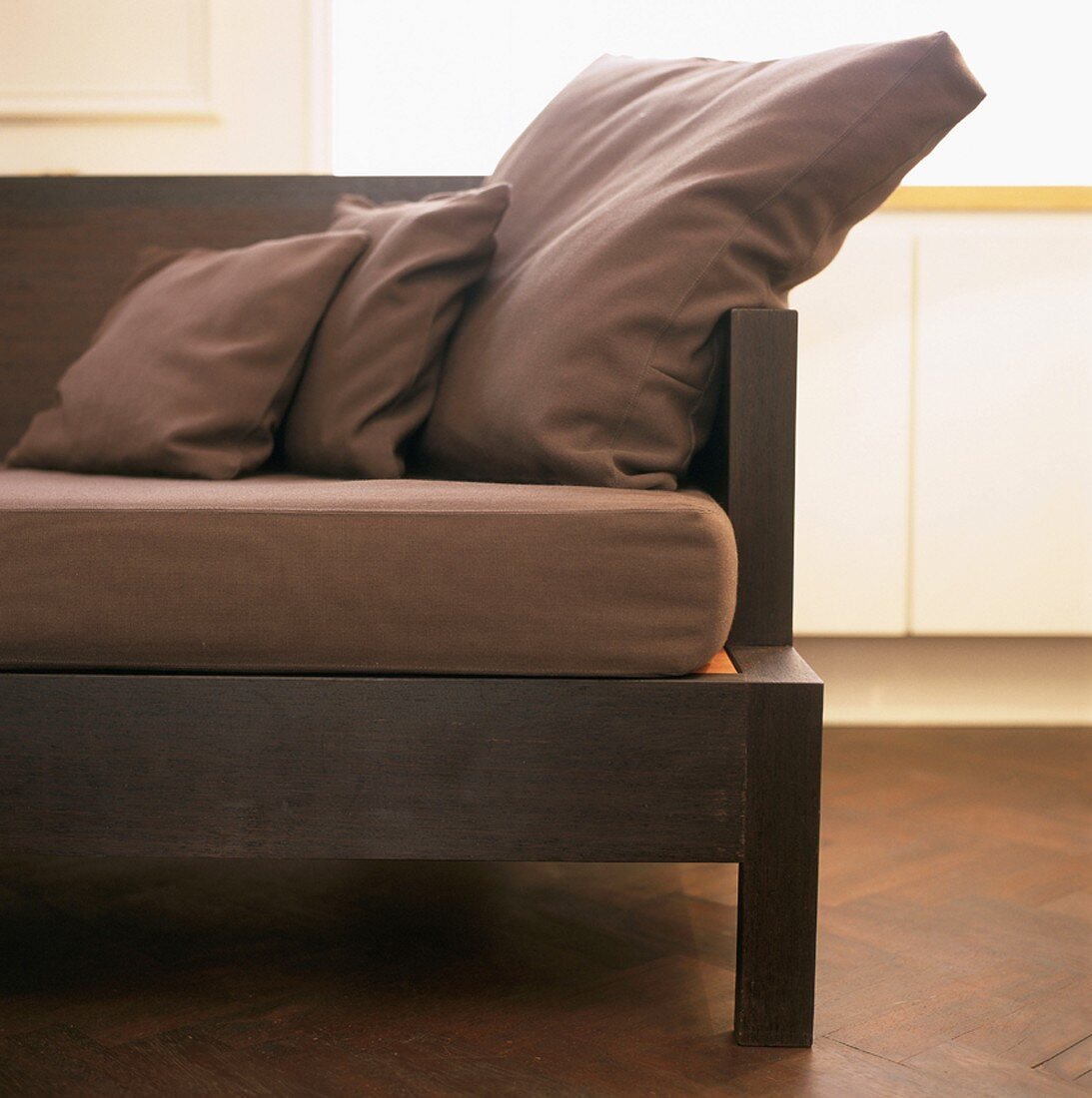 Detail eines eleganten Sofas mit Holzgestell und braunen Polsterkissen