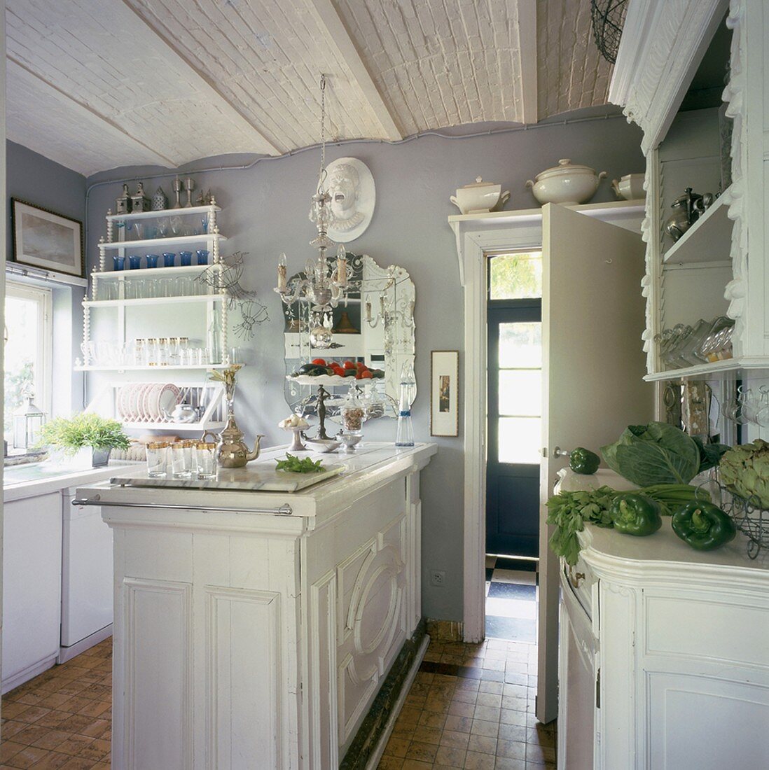 Ein Kronleuchter, ein eleganter Spiegel und dekorative Zierleisten an den Küchenmöbeln machen die verspielte Romantik der Küche aus