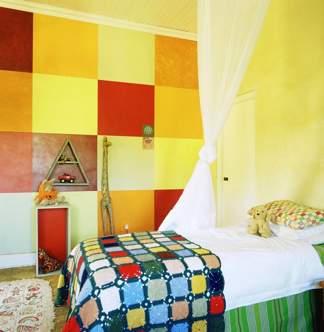 Ein kunterbuntes Kinderzimmer mit Karomuster an der Wand und einem Betthimmel über dem gemachten Bett