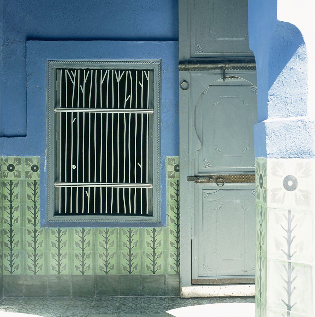Eine traditionell orientalische Holztür neben einer Fensteröffnung mit eingebautem Metallgitter