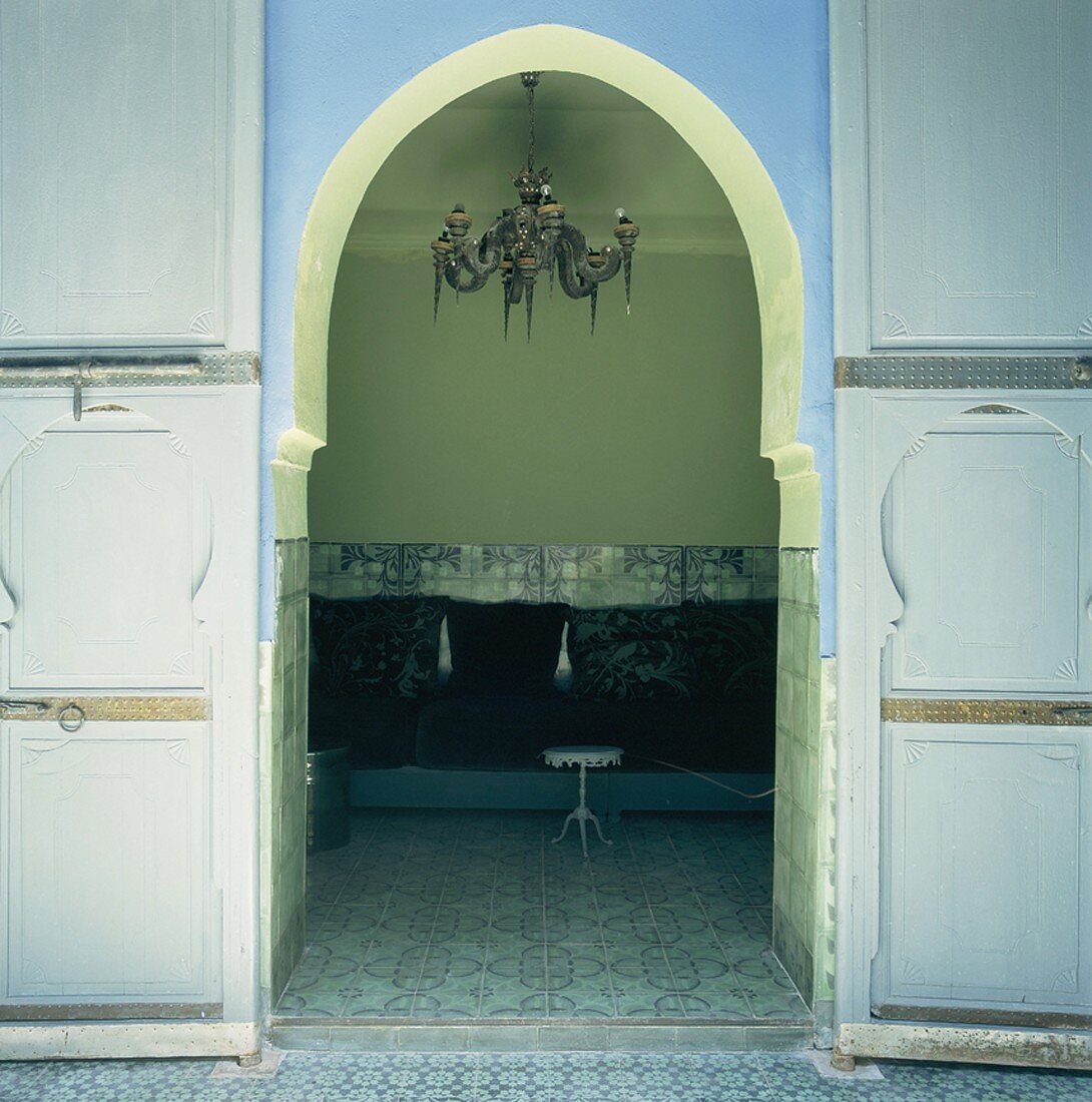 Blick durch einen Rundbogen mit traditionellen Flügeltüren in den Gangbereich eines orientalischen Hauses