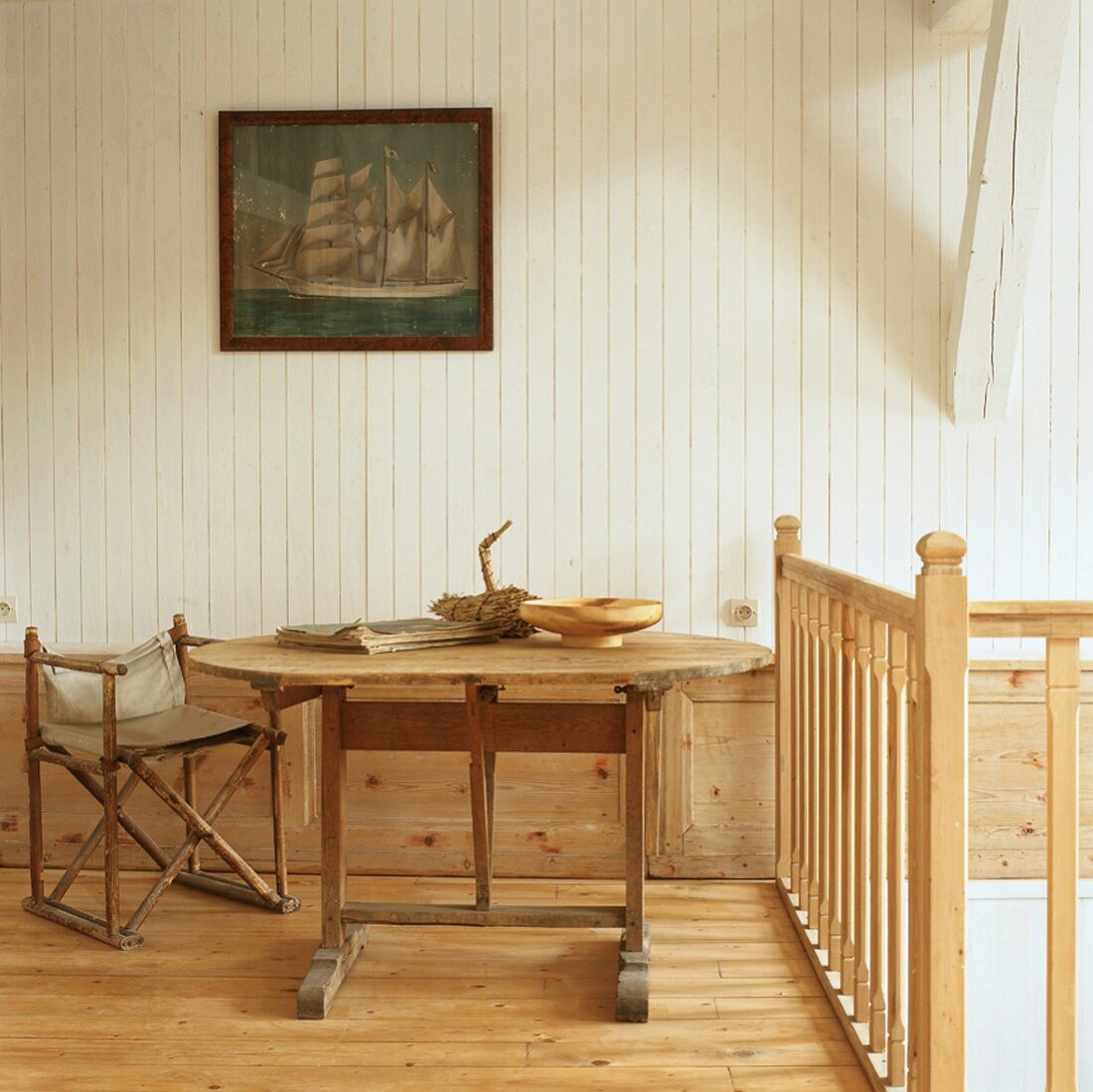 Ein alter Klappstuhl neben einem rustikalen Holztisch im ländlichen Ambiente eines Bauernhauses