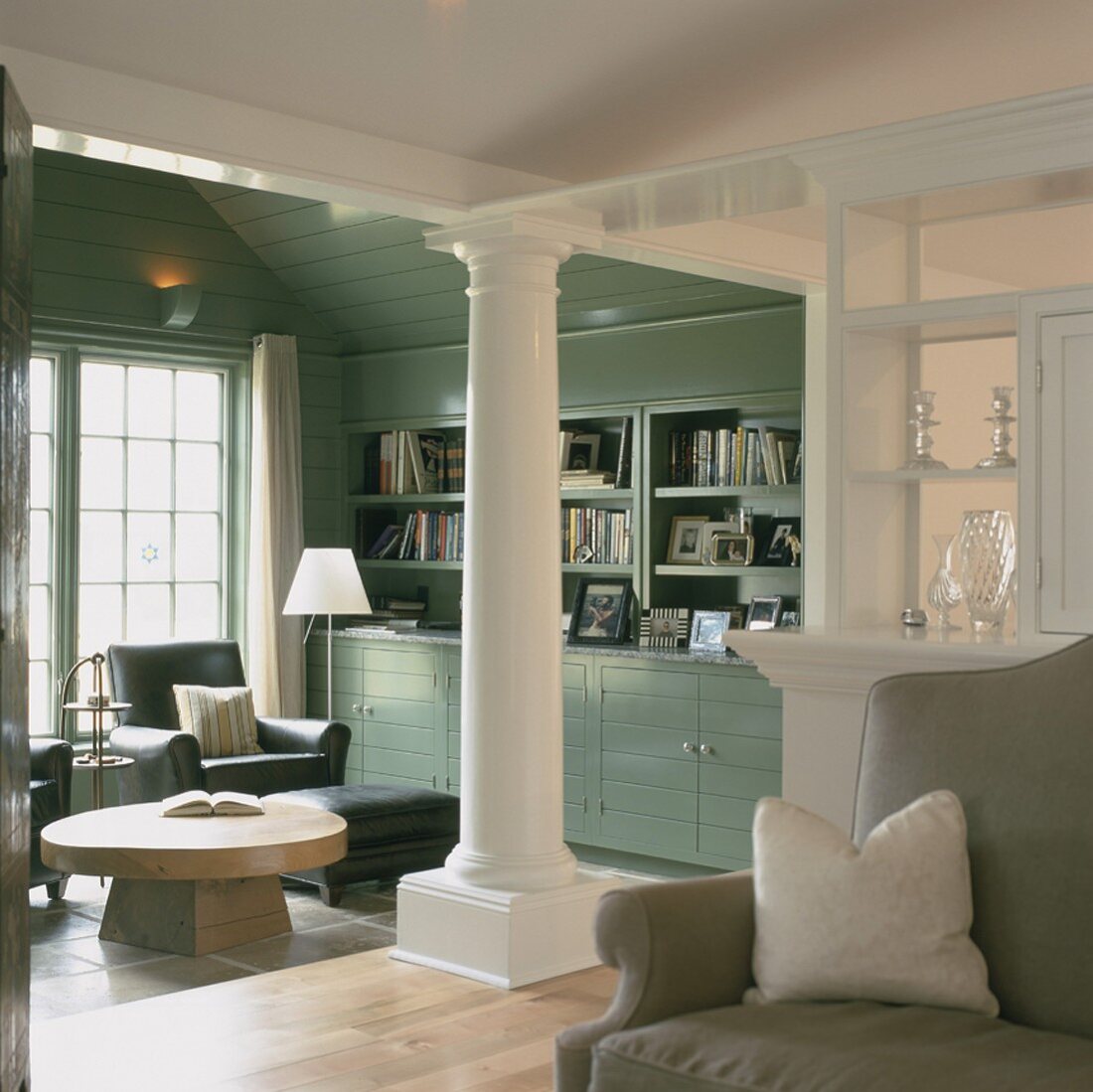Eine weiße Säule dient in dem eleganten Wohnzimmer mit Einbauregal als klassisches Gestaltungselement