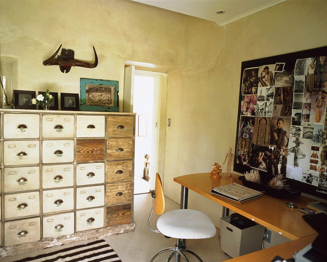 Eine Fotocollage auf dem Schreibtisch neben einem antiken Schubladenschrank