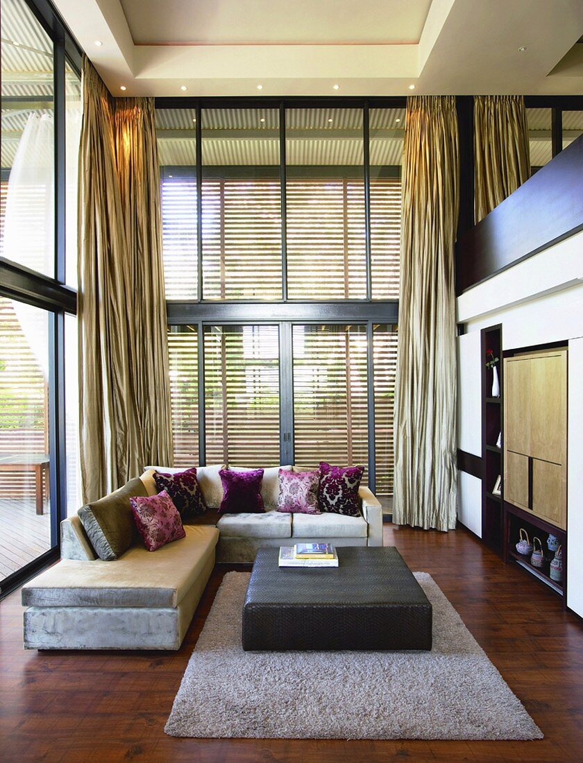 Verglaster Wohnbereich mit modernem Ecksofa und edlem Mahagoniparkett