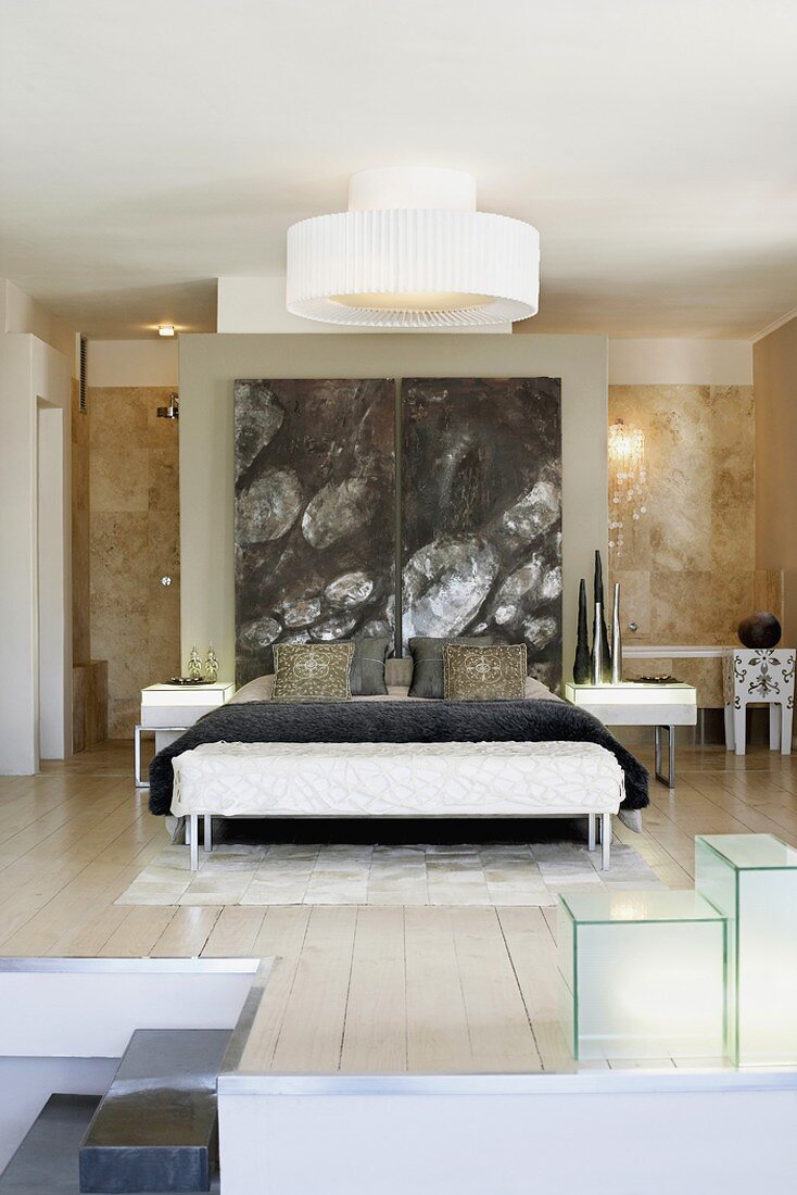 Ein abstraktes Gemälde ziert die Trennwand, die das moderne Schlafzimmer vom dahinterliegenden Badezimmer trennt
