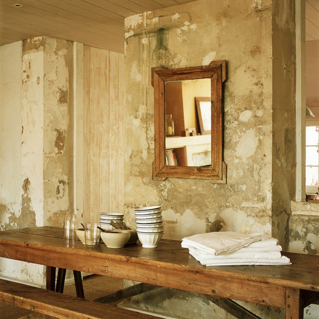 Antiker, rustikaler Holztisch und Spiegel vor einer alten, abgenutzten Wand