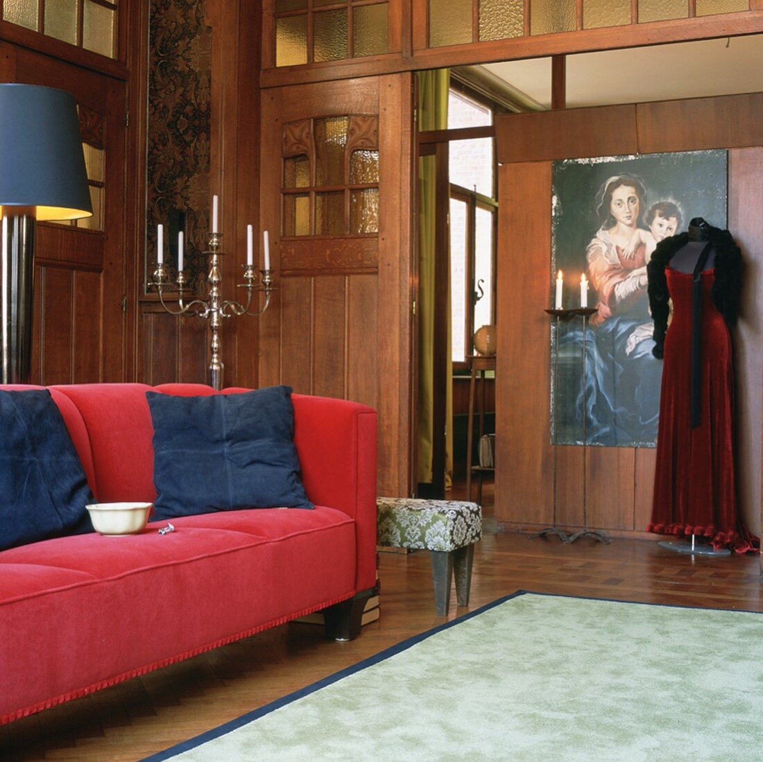 Rotes Sofa mit blauen Kissen in einem historischen, komplett holzvertäfelten Wohnraum