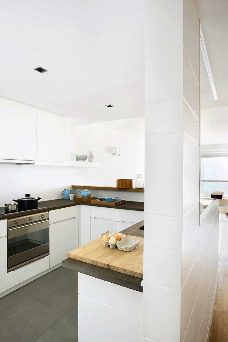 Moderne, offene Küche mit weissen Fronten und schwarzer Arbeitsfläche