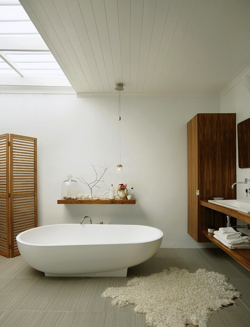Moderne Holzeinrichtung und freistehende Badewanne mit Fellvorleger im minimalistischen Badezimmer