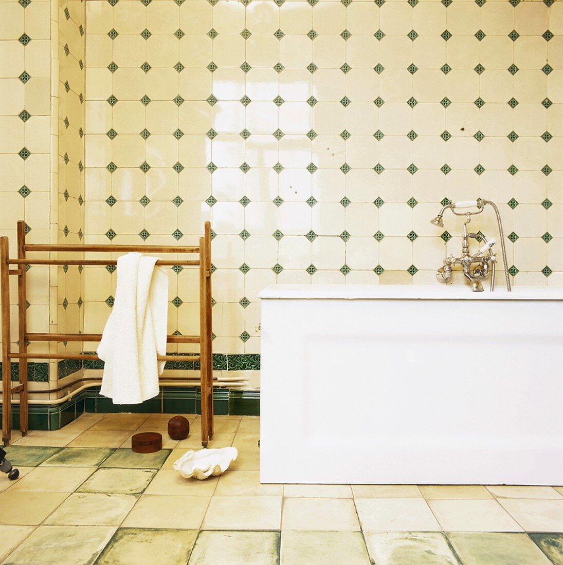 Eckige Badewanne und Handtuchdiener vor einer Fliesenwand mit Rautenmuster
