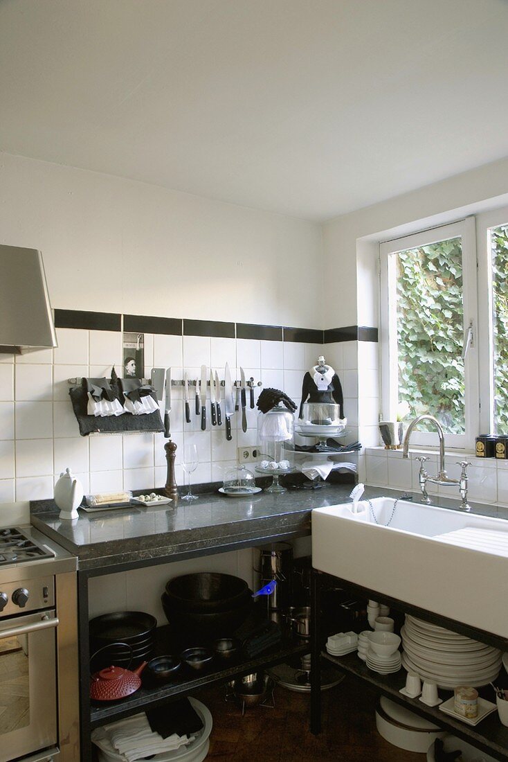 Eine Küchenzeile in Schwarzweiss mit offenen Unterschränken und Granitarbeitsplatte
