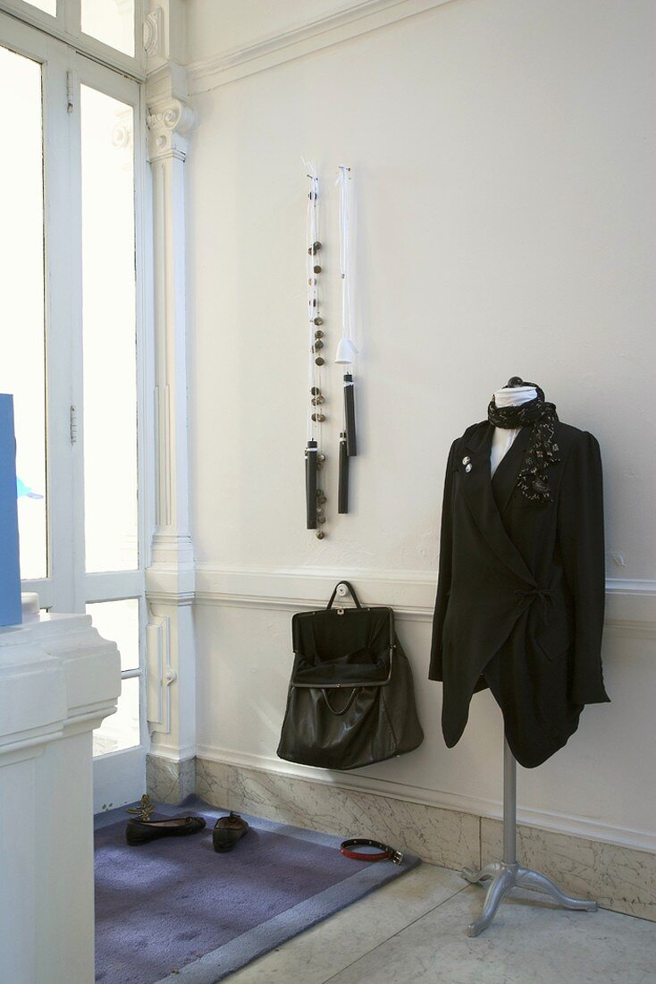 Schneiderpuppe und schwarze Handtasche in einem Vorraum mit Marmorboden