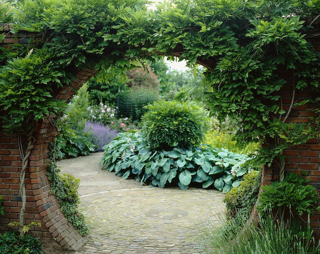 Blick durch runde Maueröffnung in Gartenanlage