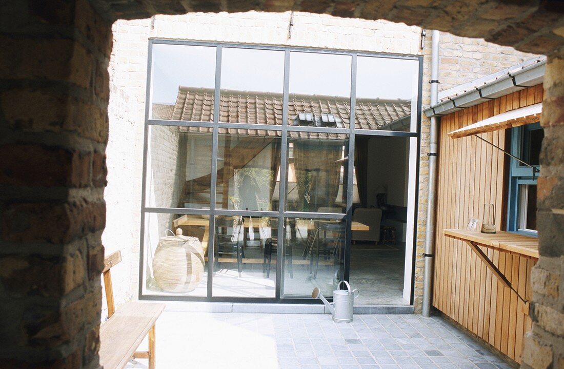 Blick aus einem Durchgang in den Innenhof mit Theke und reflektierender Glasfront