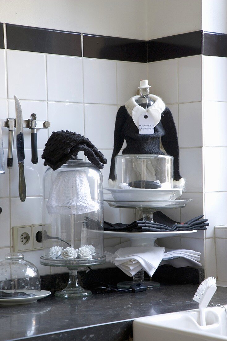 Küchenausschnitt mit Utensilien und Dekorationsobjekten in Schwarz und Weiß auf schwarzer Arbeitsplatte