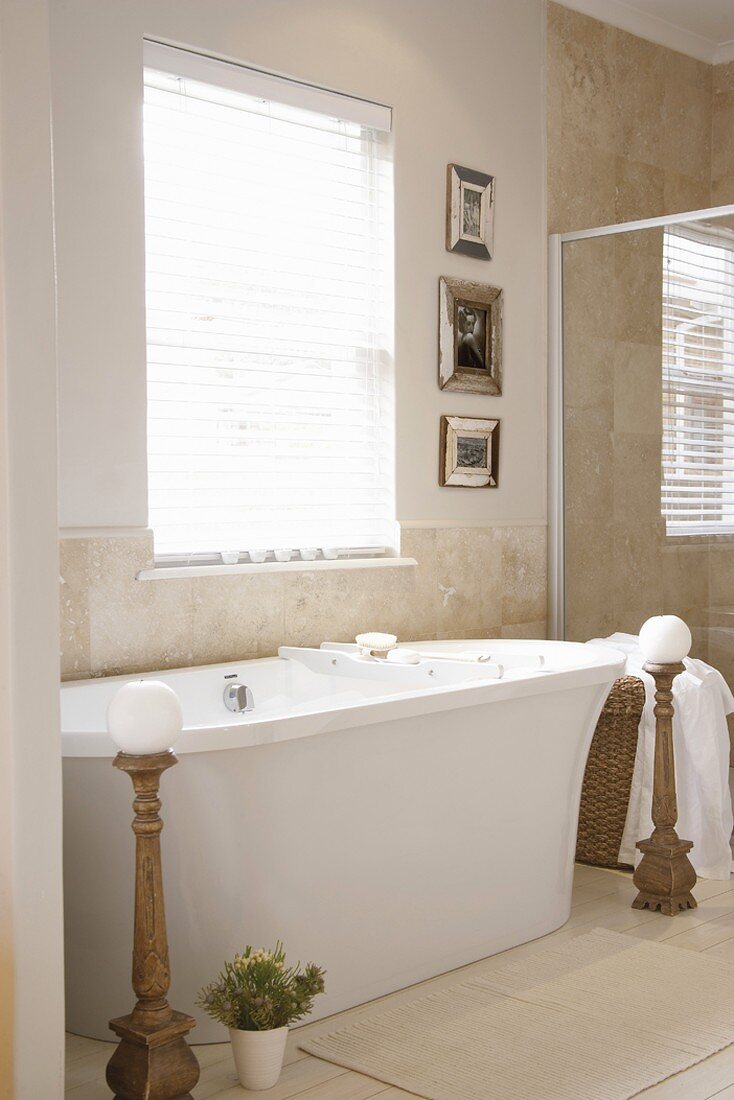 Freistehende, moderne Badewanne in Badezimmer mit Marmorfliesen an der Wand und einem weissen Holzdielenboden