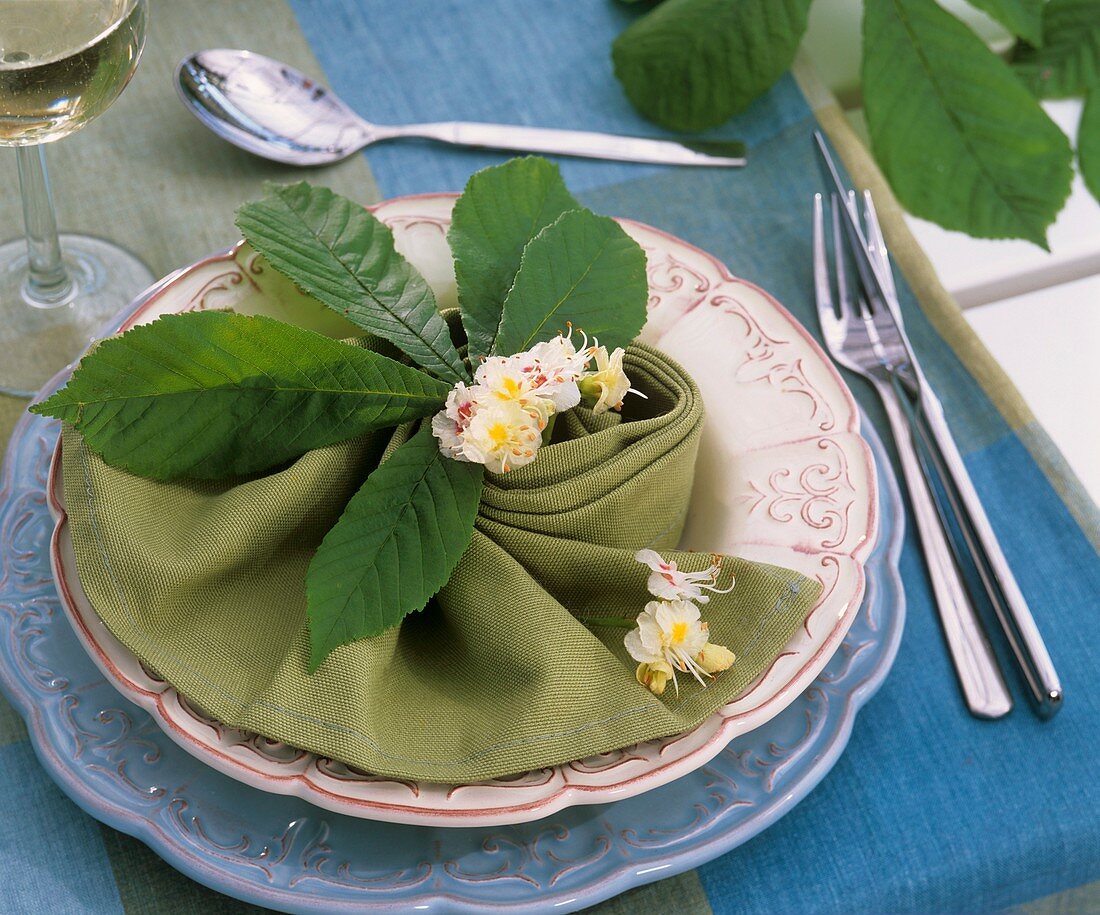 Place-setting with chestnut flowers and leaf