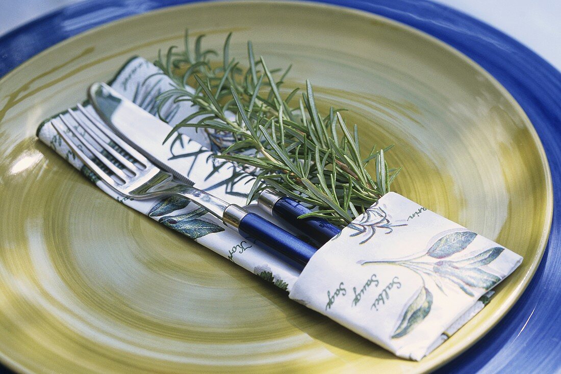 Place-setting with rosemary and herb-patterned fabric napkin