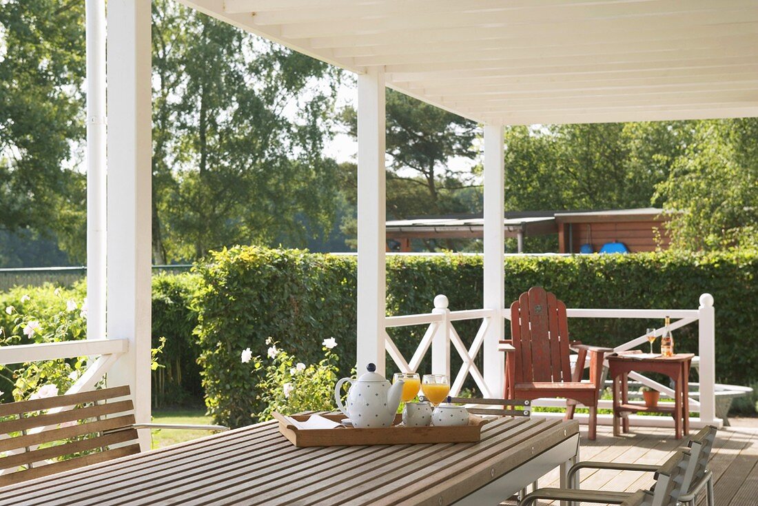 Überdachte Terrasse mit Holzgeländer & Gartenmöbeln