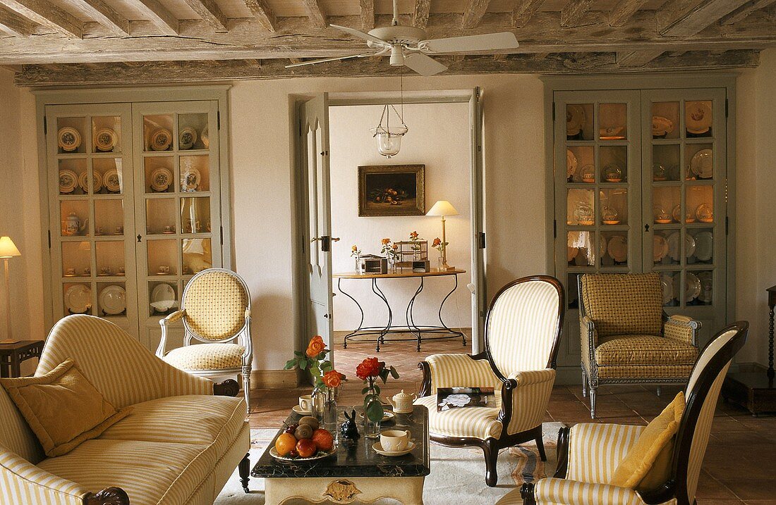Wohnzimmer in Landhaus mit Sofa, Sesseln, Couchtisch & eingebauten Wandschränken für Geschirr